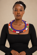 Naisula Maasai Collar Necklace with blue, red, white, green, orange and black beadwork, worn with a black dress