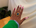 Asali Ring - deep blue oval stone in ornate hammered gold frame worn on hand