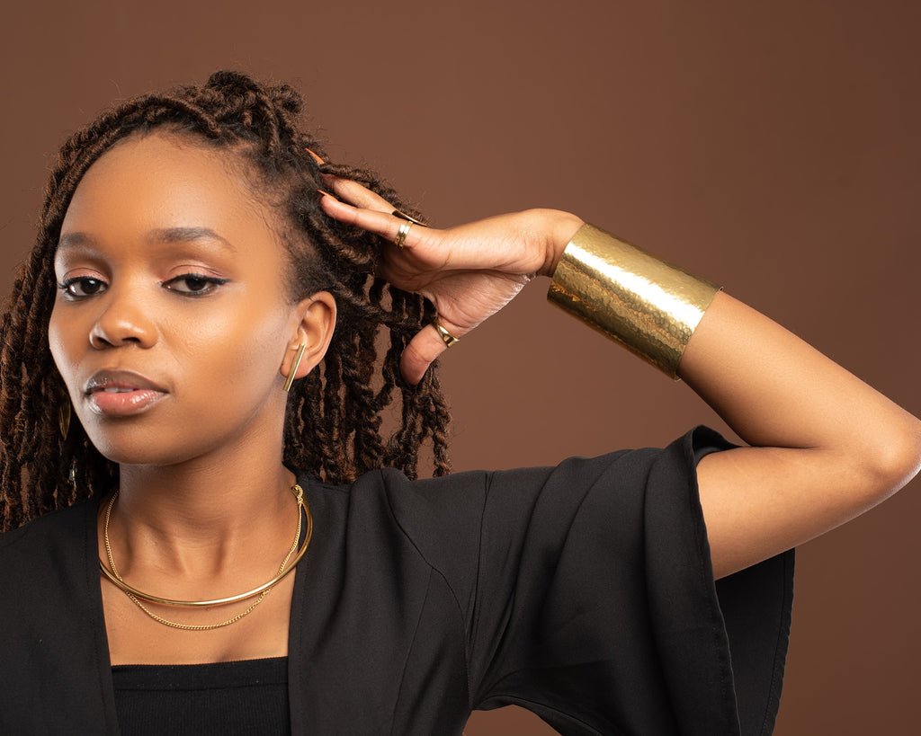 Amani Cuff - wide hammered brass cuff worn with gold necklace, editorial shot