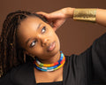 Amani Cuff - wide hammered brass cuff worn with multicolour beaded necklace, editorial shot